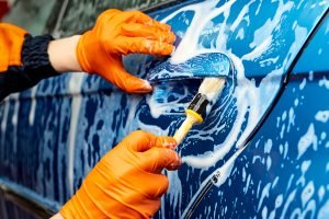 Pulizia esterna dell'auto con spugna e shampoo