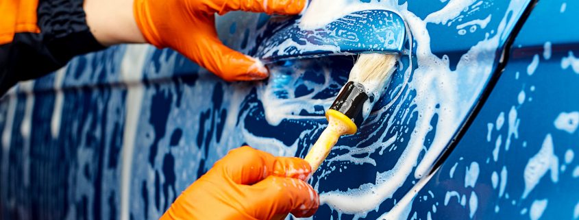Pulizia esterna dell'auto con spugna e shampoo