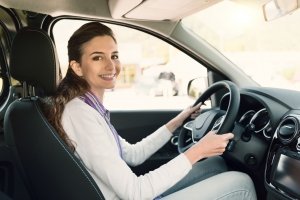 Una giovane donna guida l'auto con le mani sul servosterzo