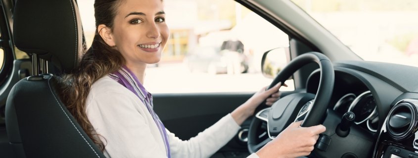 Una giovane donna guida l'auto con le mani sul servosterzo