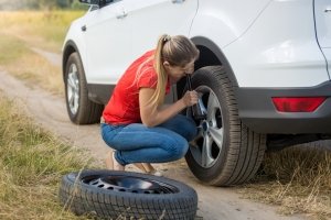 Una ragazza sta sostituendo la gomma forata della sua auto