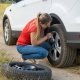 Una ragazza sta sostituendo la gomma forata della sua auto